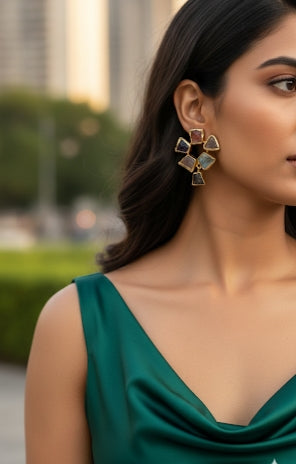 Close-up of gold plated cluster earrings set with raw, earth-tone stones.