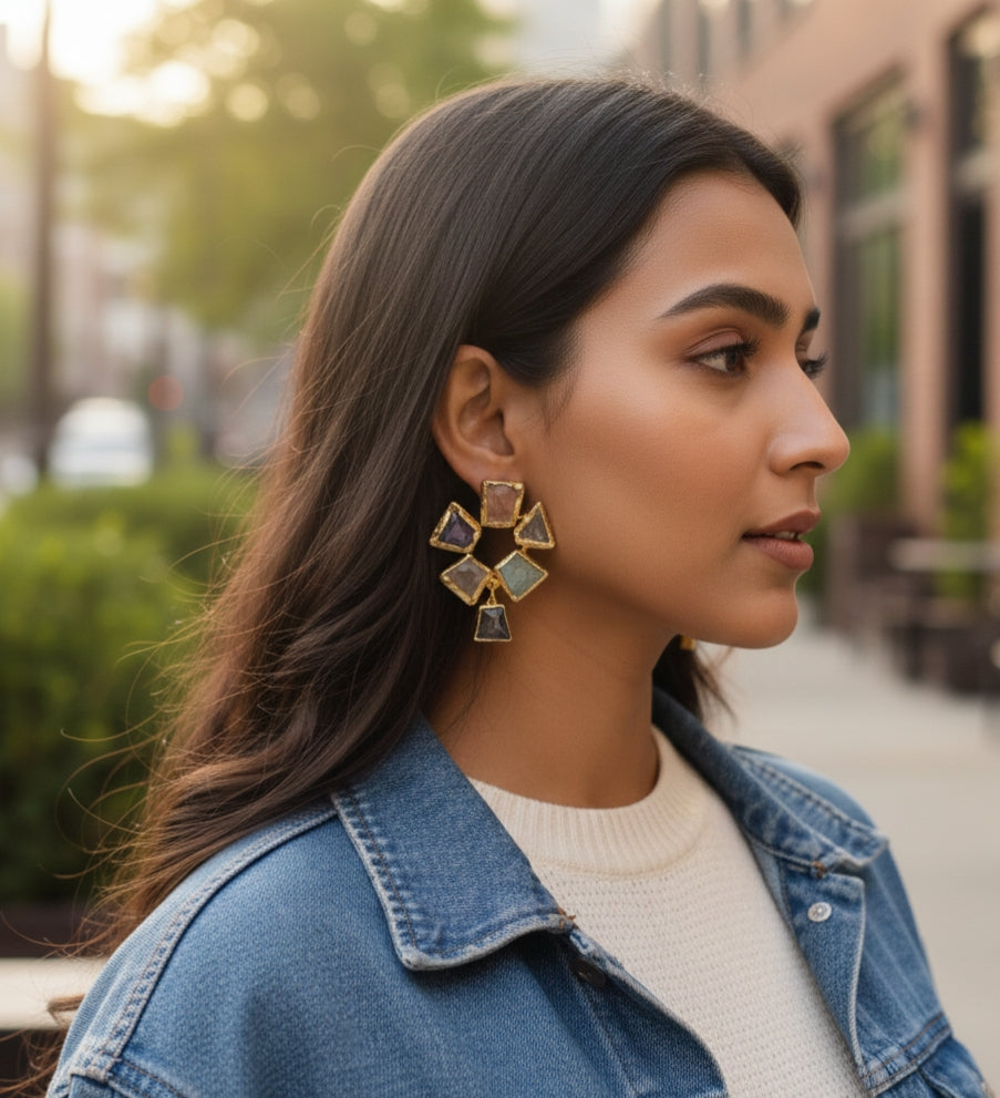 Close-up profile view of artisan gold earrings with raw cut semi-precious gemstones.