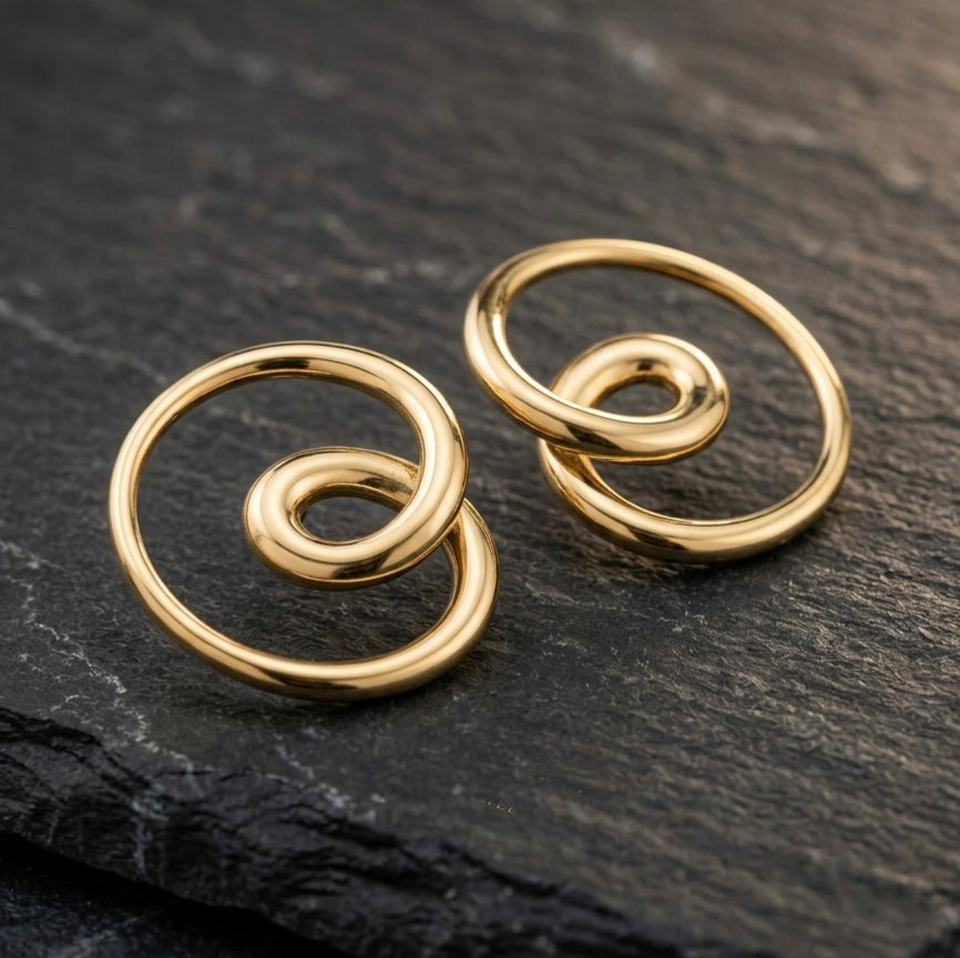 Pair of gold spiral western earrings on a dark stone surface